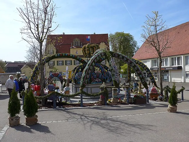 Der traditionelle Osterbrunnen in Schechingen, geschmückt mit Grün und bunten Eiern, ein beliebter Anziehungspunkt und kultureller Höhepunkt für Besucher und Einheimische.