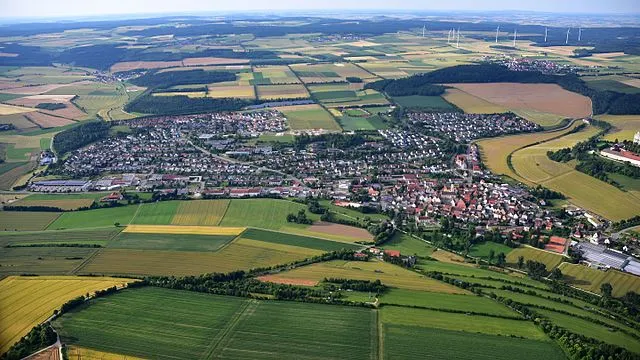 Panoramaansicht der Stadt Neresheim, eingebettet in die malerische Landschaft des Ostalbkreises, mit historischen Gebäuden und grünen Feldern im Hintergrund.